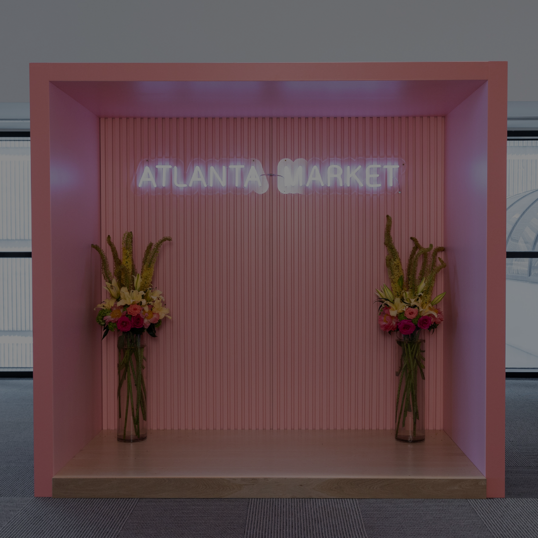 Picture of a photo booth in the Atlanta Market Center that is pink and has vases of flowers.