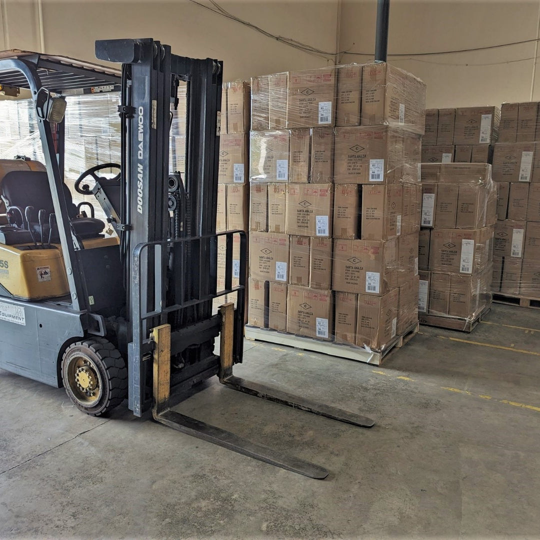 A parked forklift next to a load of packed pallets.
