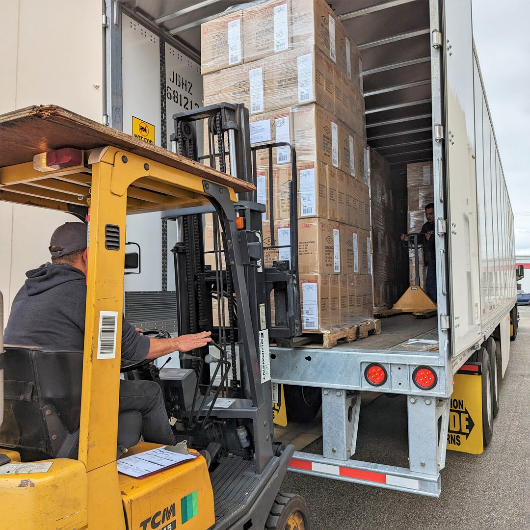 A forklift loading a pallet onto a delivery trailer.